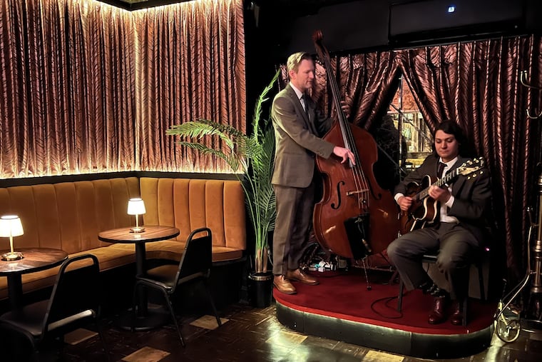 Doug Drewes tunes up on bass and Huck Browne plays guitar in the President's Room at Palizzi Social Club. where Greg Vernick was member no. 186.