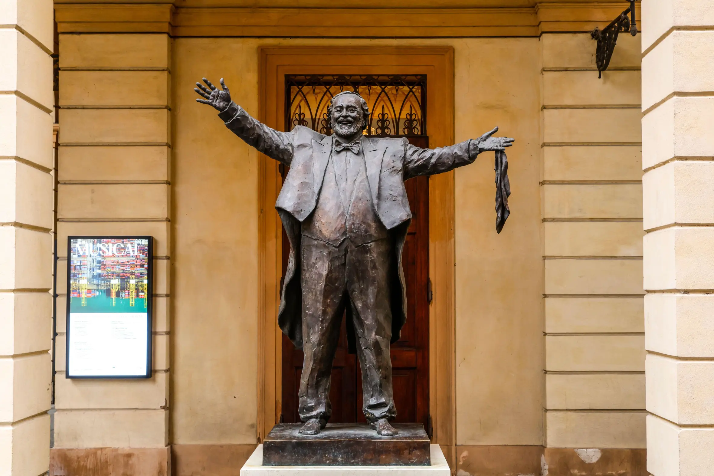 Bronze sculpture of Luciano Pavarotti with open arms.