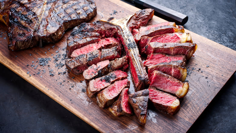 A close-up of a bistecca alla fiorentina on a wood cutting board.