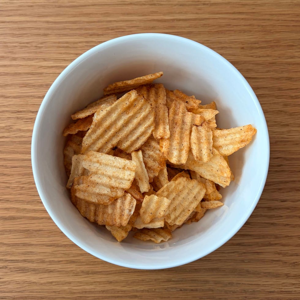 Bowl of wavy potato chips on a wooden surface