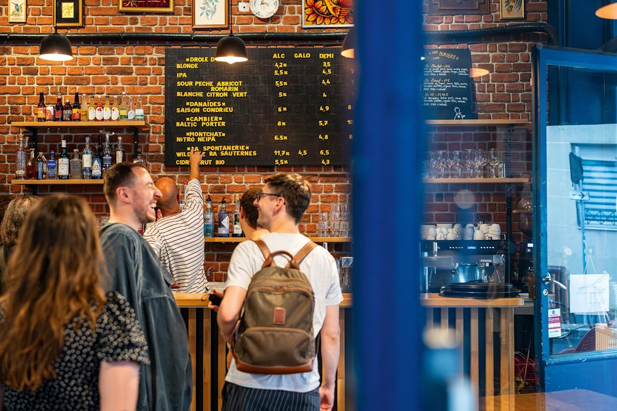 The interiors of a laid-back microbrewery with laughing guests lining up to order at the bar.