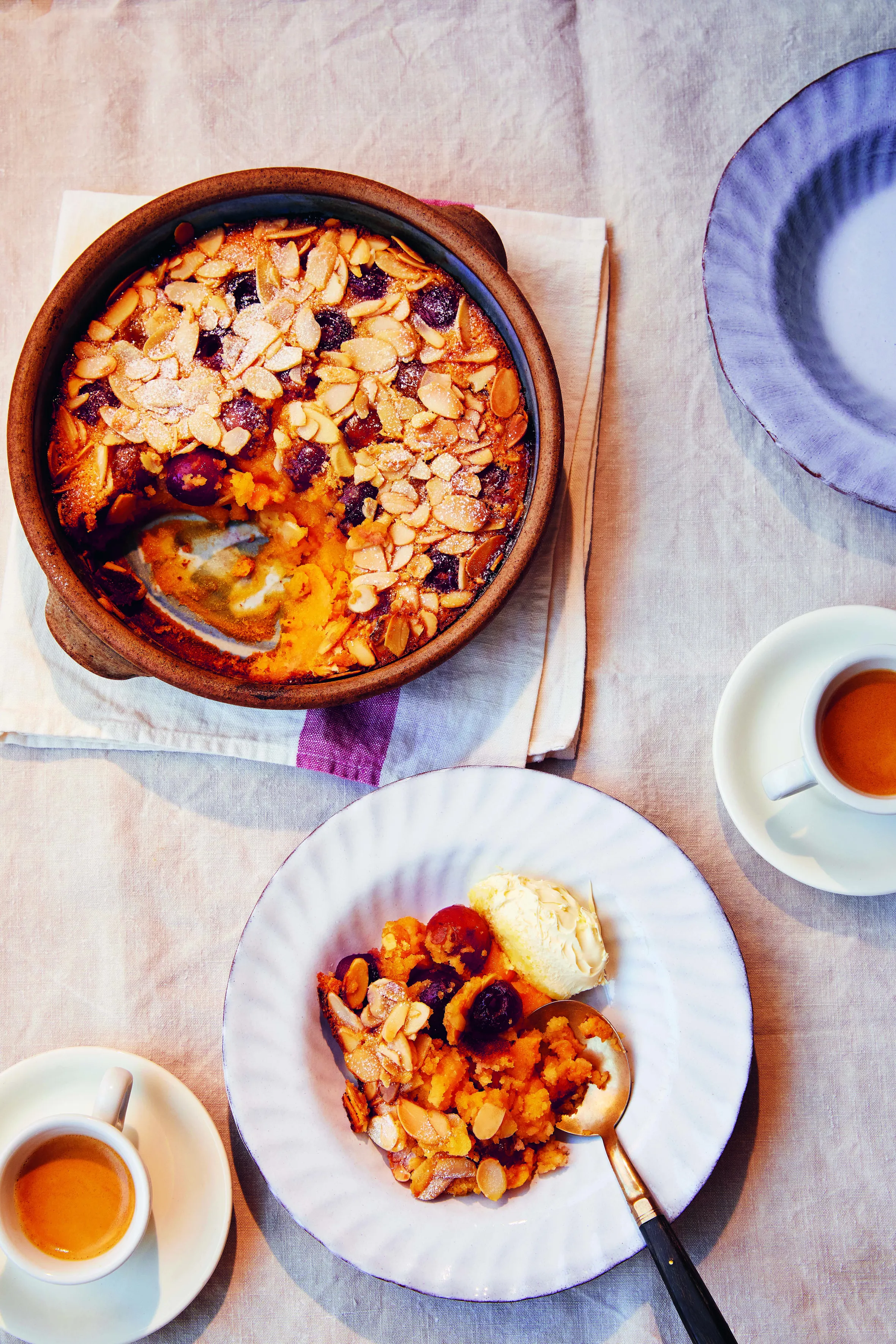 Cherry and Almond Clafoutis in a baking dish and served on a plate with ice cream.