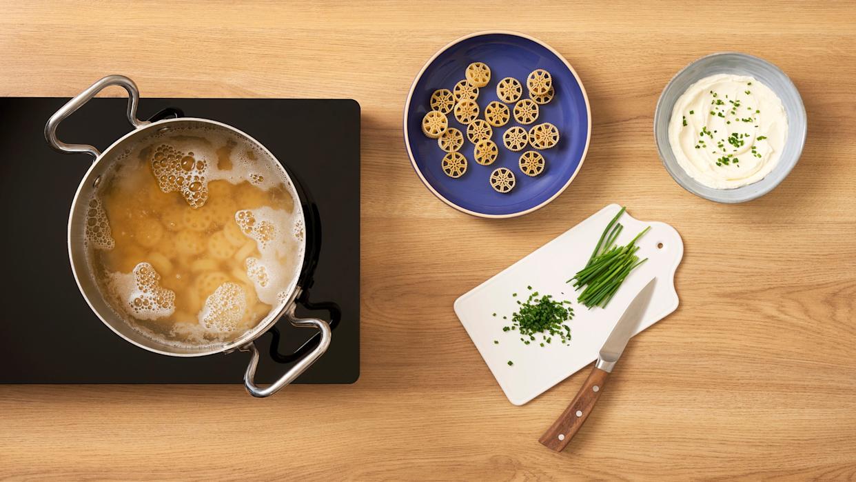 Racing tire shaped pasta in pot of boiling water alongside the dried pasta on a plate