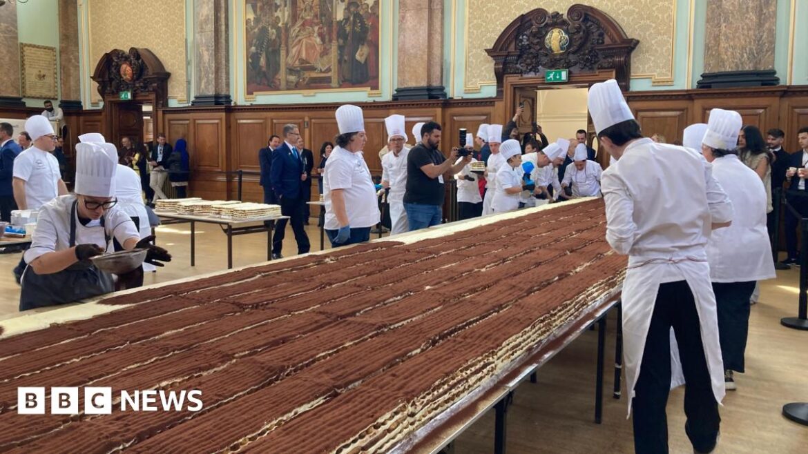 Chefs work on a long tiramisu on a table