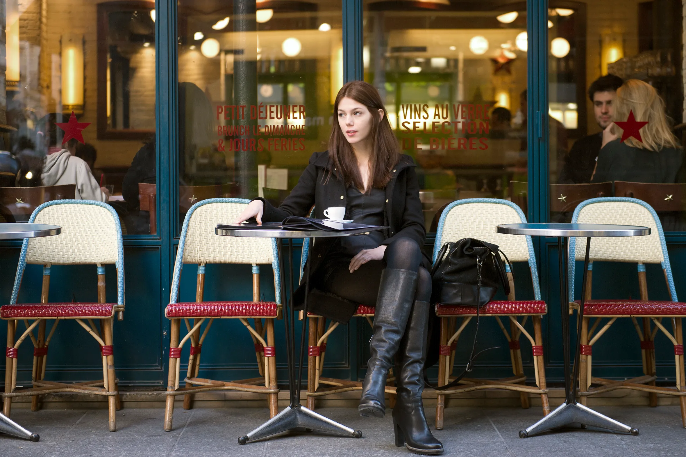 Romanian model Ioana Timoce sitting at a cafe terrace in Paris.