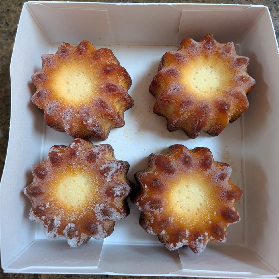 Box containing four canelé pastries.