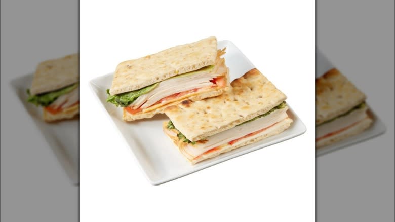 Two Kirkland Signature Chicken Sandwiches on Sprouted Grain Bread sitting on white square dish