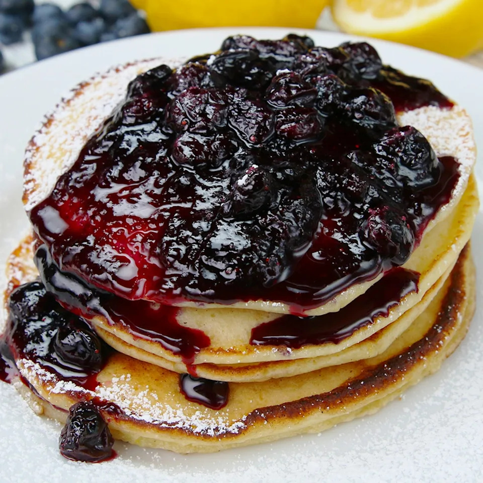 Stack of pancakes topped with a generous serving of blueberry compote on a plate