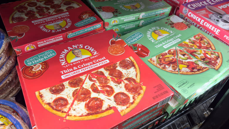 Several varieties of Newman's Own pizza are displayed in a grocery store cold case
