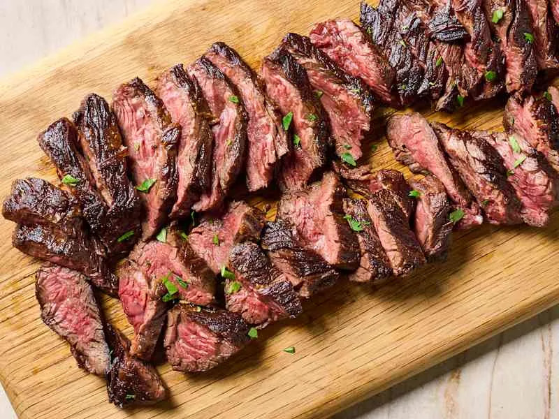 overhead shot of hanger steak on a wooden cutting board, sliced