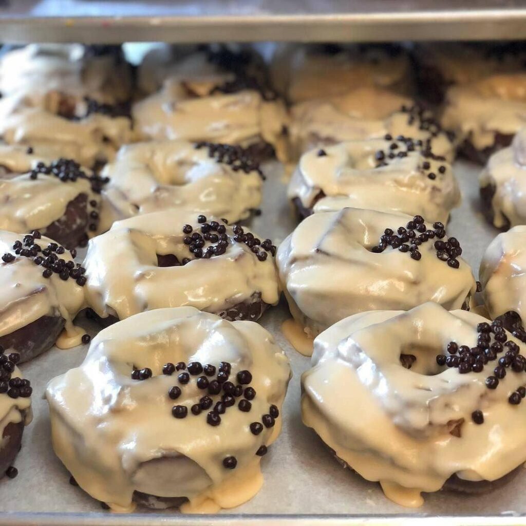 Chocolate donuts with vanilla glaze and pearls.