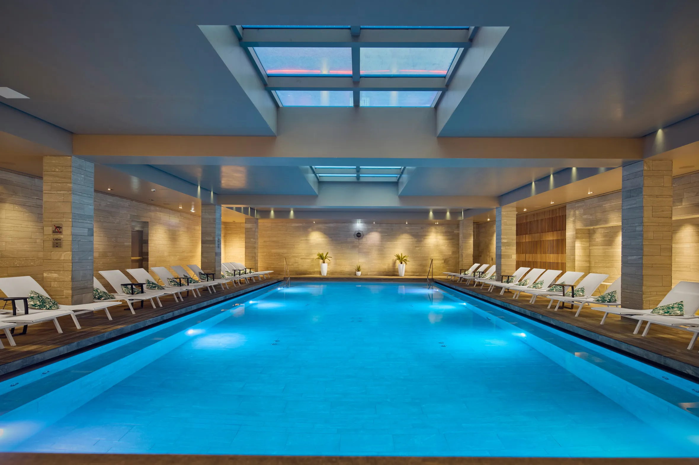 Indoor swimming pool with lounge chairs and skylights.