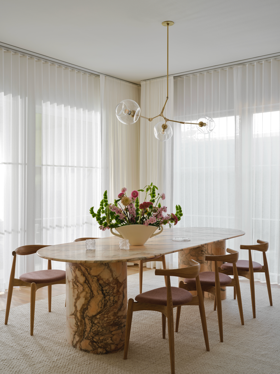 Modern dining area with marble table and floral centerpiece.
