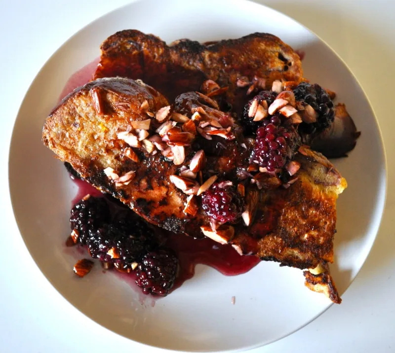 French toast topped with blackberries and chopped nuts on a white plate