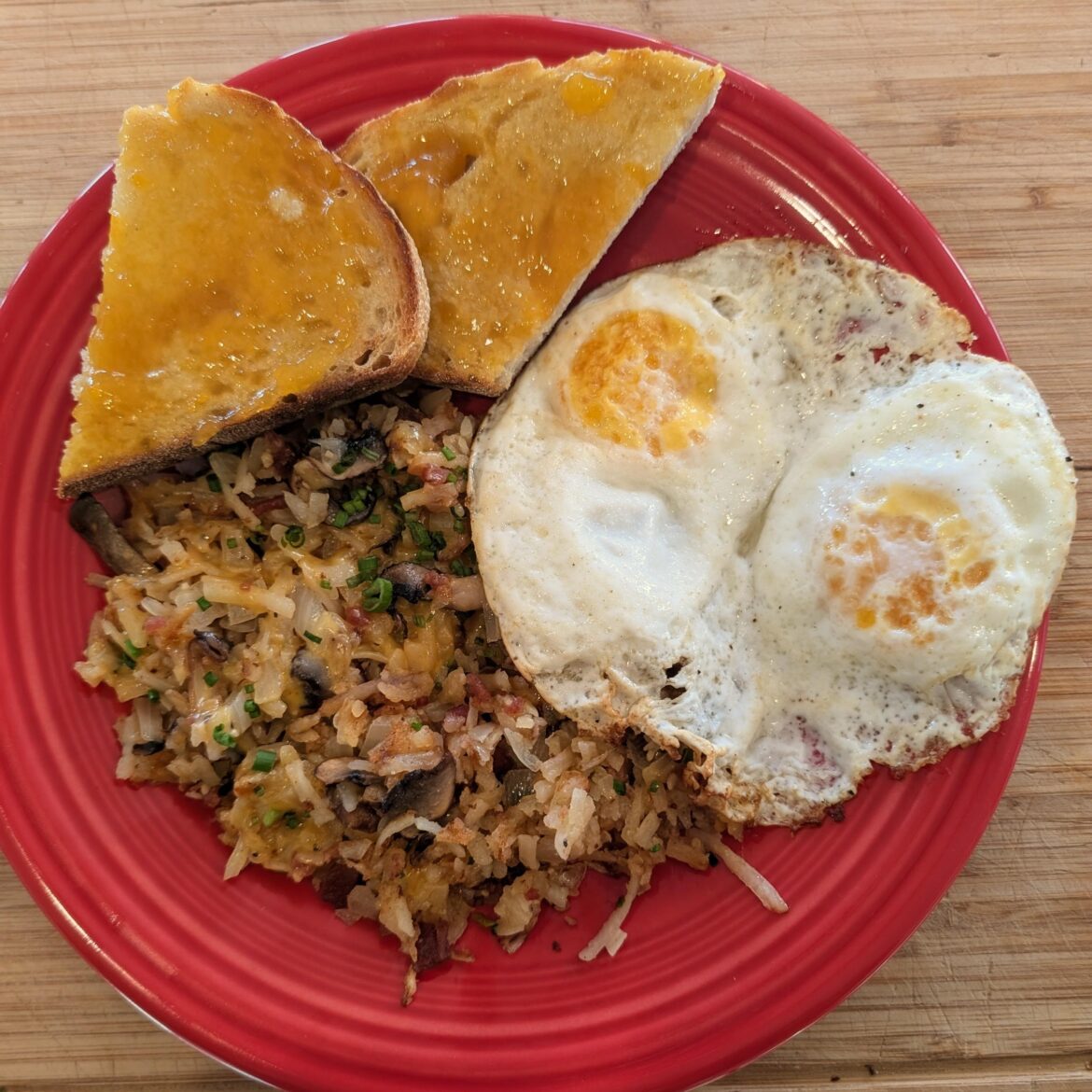 Cheesey hash browns w/ onion, mushroom, and bacon. Two eggs over easy and toast w/ peach jam.