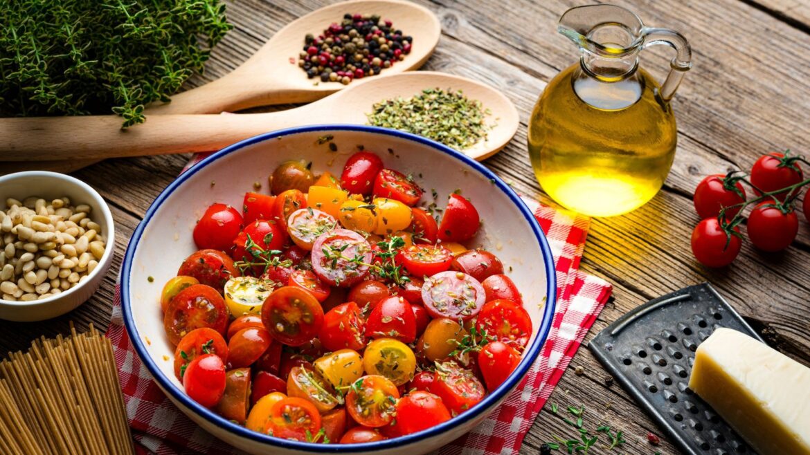 Tomatoes in a bowl with olive oil, wholegrain pasta and herbs, part of the Mediterranean diet