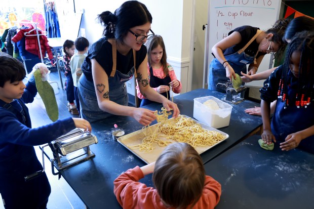 Teacher Ariana Lopez, center, assists children as they make pasta from scratch during a cooking class at the Schoolhouse Kitchen + Studio in Chicago, March 25, 2026. (Antonio Perez/Chicago Tribune)