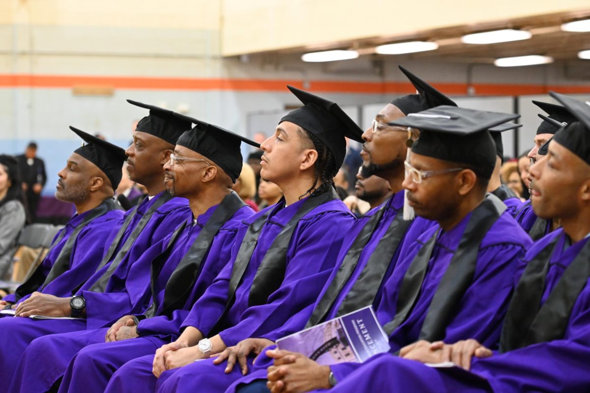 Graduation students in robes sit in a row.