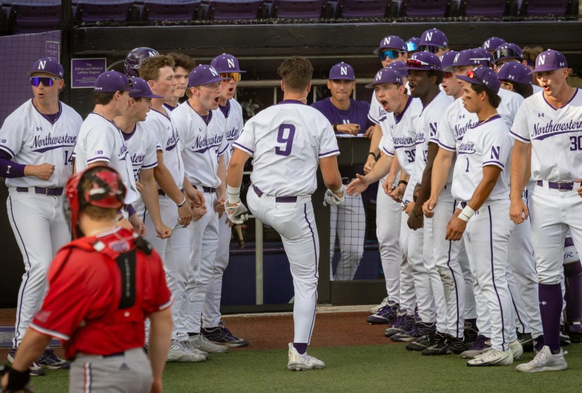 Baseball players in white cheer around another player in white.