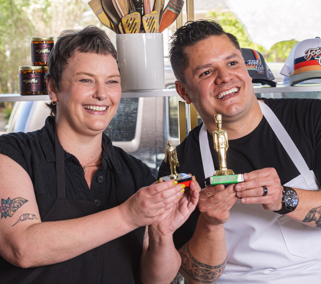 two people in aprons holding trophies