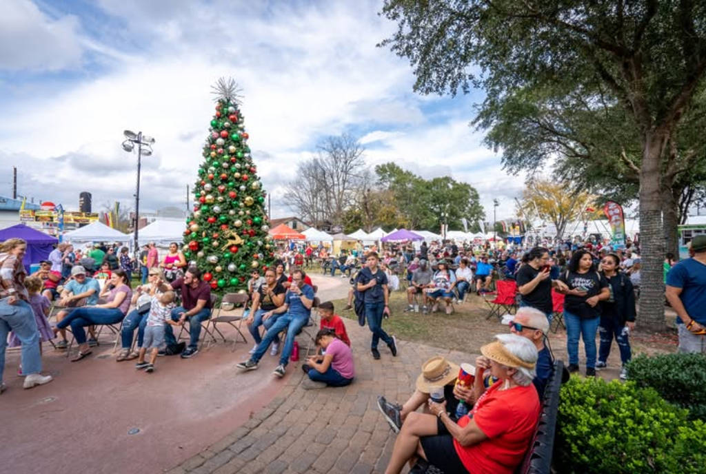 Image shows a group of people hanging around a Christmas tree at the Tomball German Christmas Market.