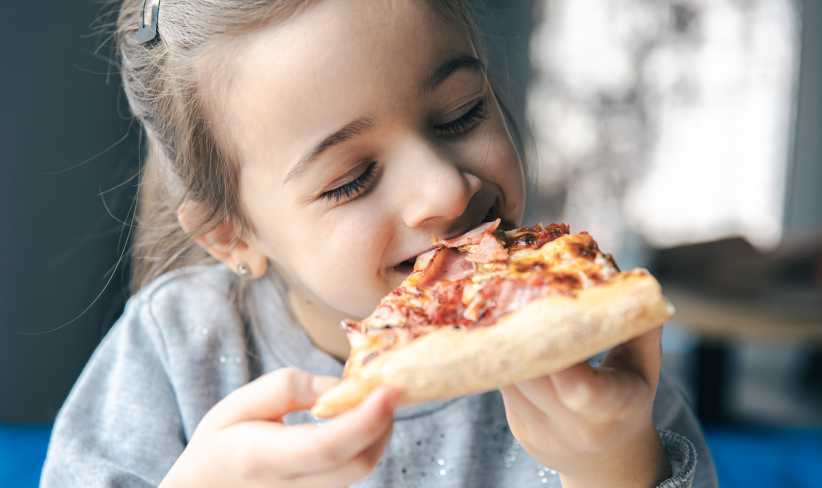 The Best Pizza Spots in Westchester Right Now, Portrait of a little girl with a piece of pizza, the child appetizingly eats pizza.