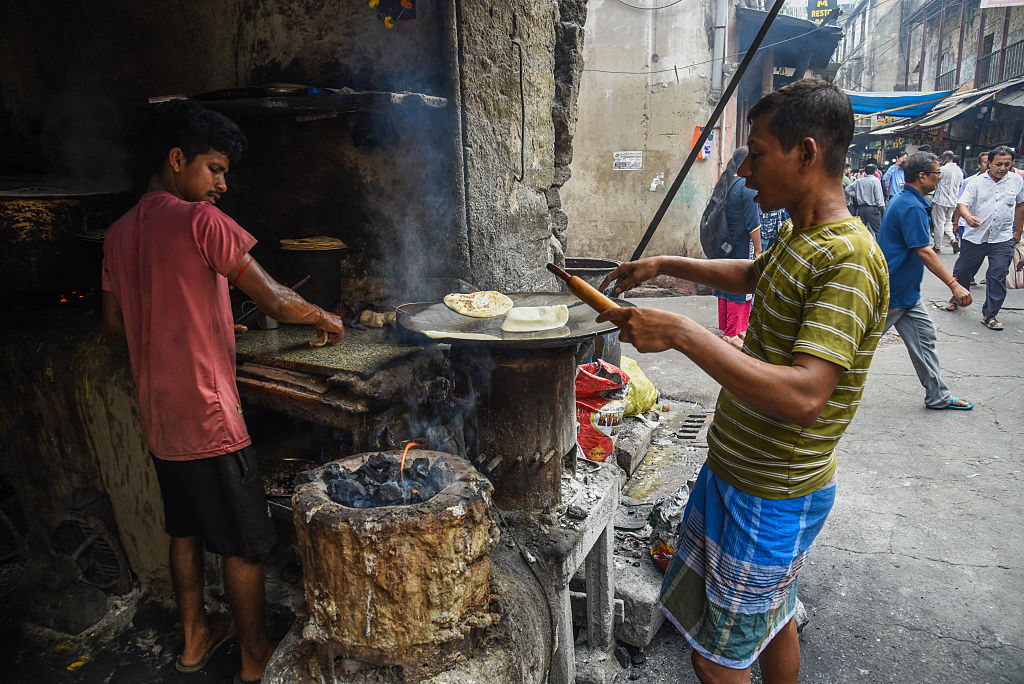Two men making street food using coal for fuel