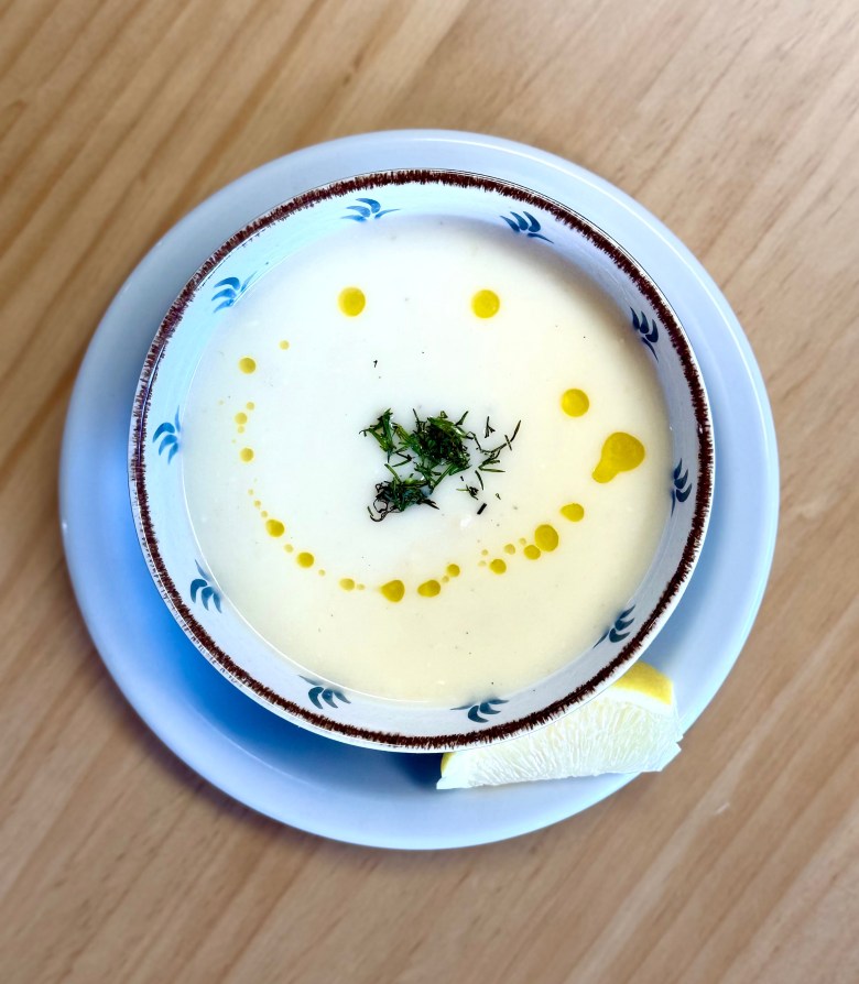 overhead view of a pale soup with dill and sprinkled olive oil