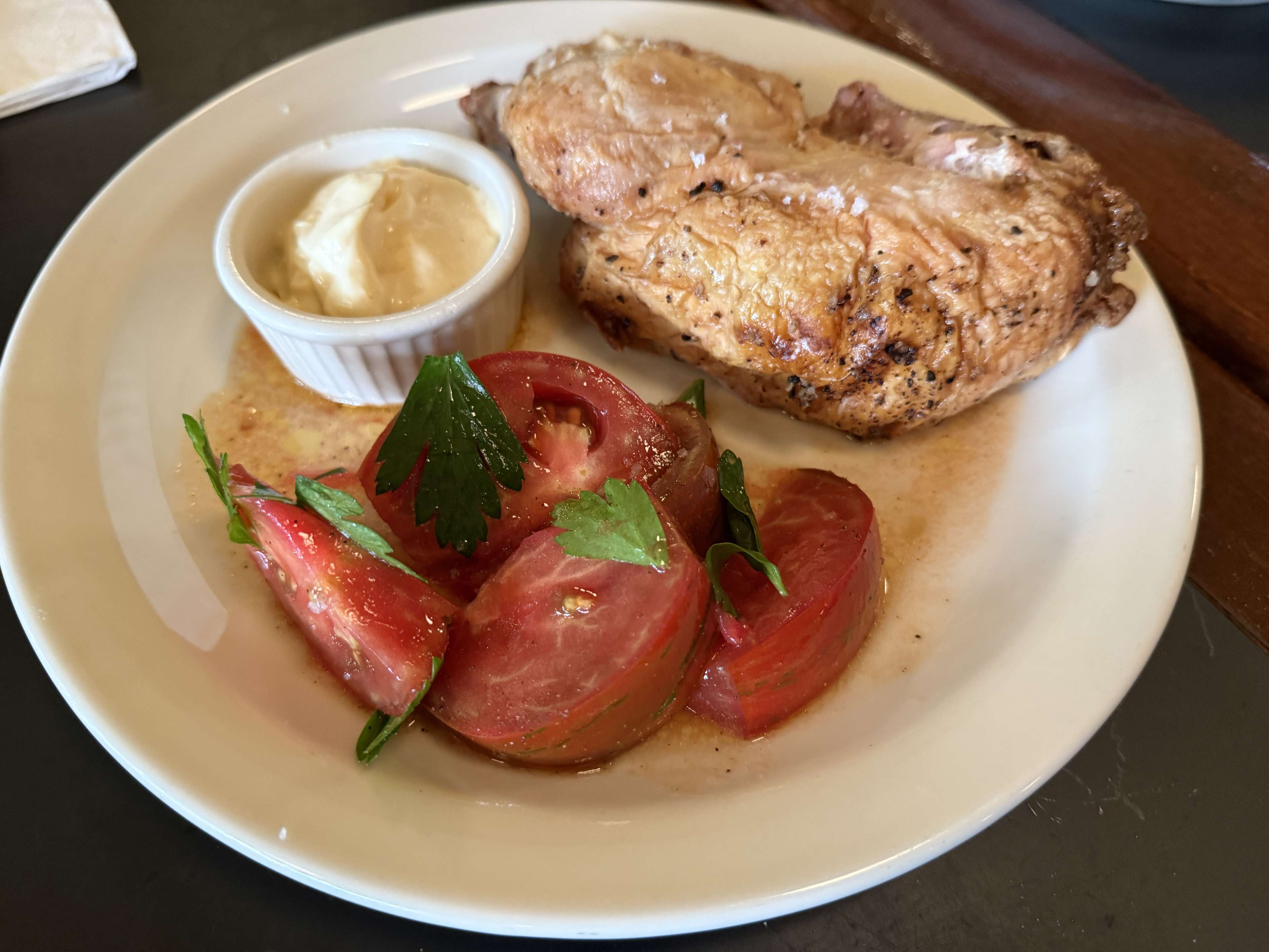 a half-chicken with mayonnaise and a tomato salad
