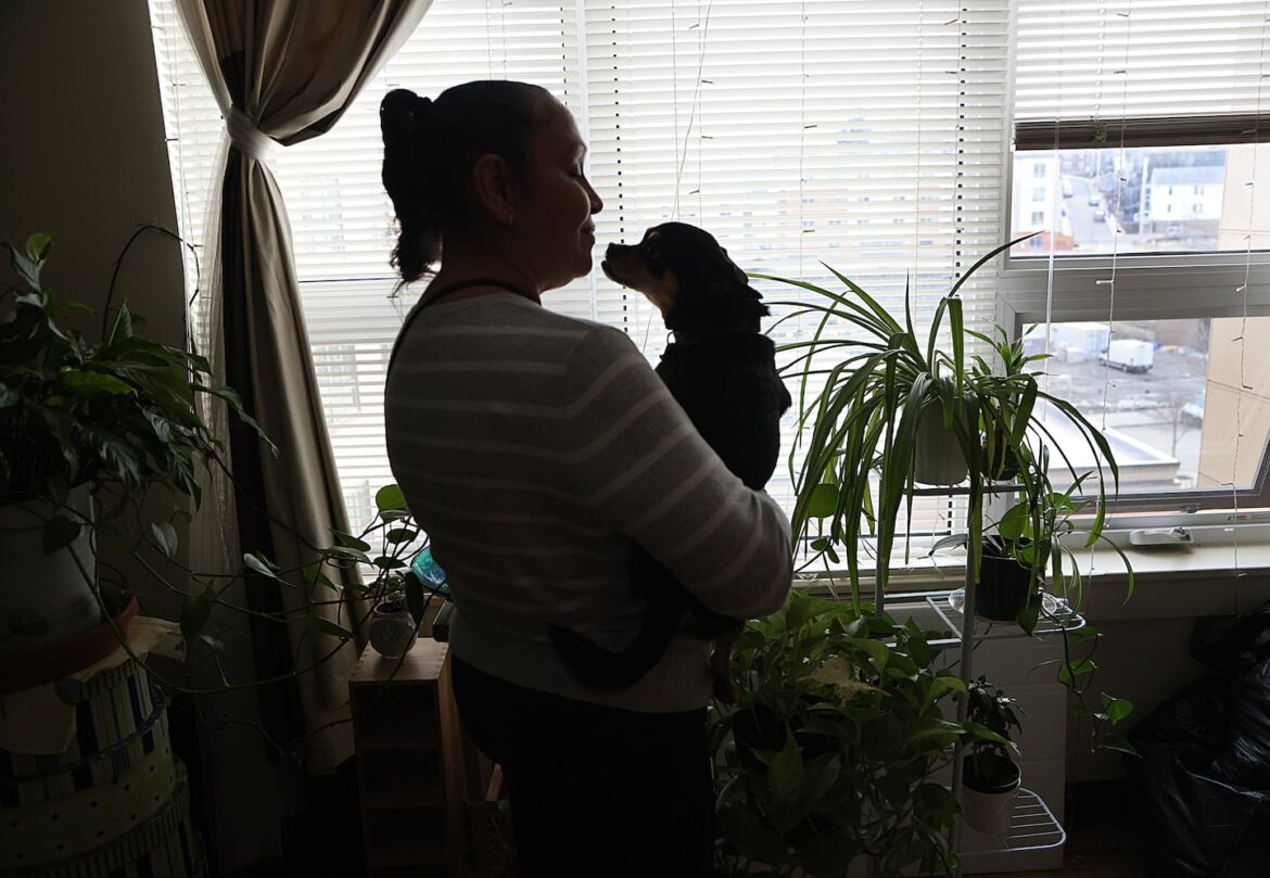 YmaNini LaCourt holds her dog Mizzo at her apartment in Boston, on Mar. 30. She gets dog food from the Boston Animal Rescue League pet food pantry.