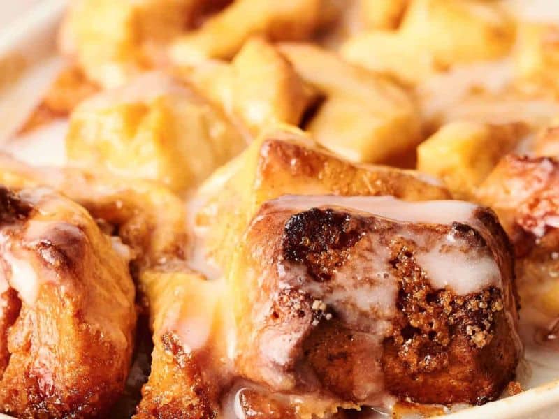 Close-up of a dish of warm cinnamon rolls topped with white glaze.