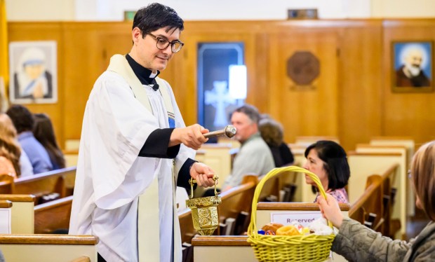 Rev. Giuseppe Esposito sprinkles holy water on prepared Easter baskets Saturday, April 4, 2026, during a blessing of the food baskets on Holy Saturday at St. Anne Catholic Church in Bethlehem. (April Gamiz/The Morning Call)