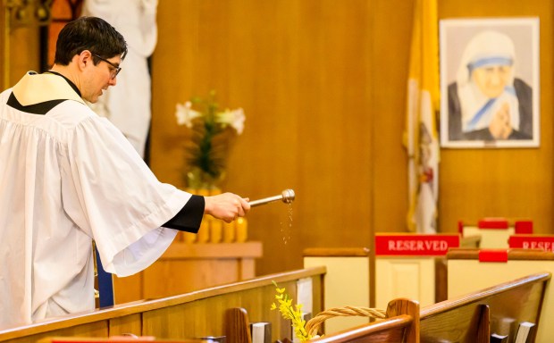 Rev. Giuseppe Esposito sprinkles holy water on prepared Easter baskets Saturday, April 4, 2026, during a blessing of the food baskets on Holy Saturday at St. Anne Catholic Church in Bethlehem. (April Gamiz/The Morning Call)