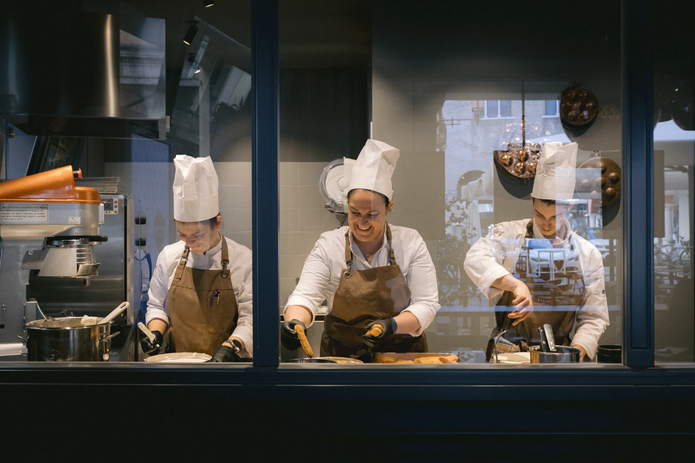 Three chefs in white uniforms and brown aprons prepare tiramisu at Tiramisù Le Beccherie in Treviso, Italy.