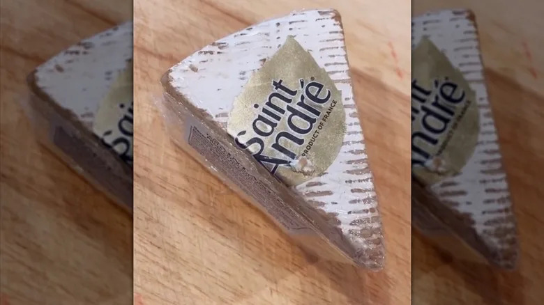 Saint André Triple Crème Brie in packaging on wood cutting board.