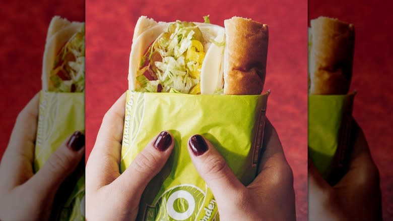 woman holding a wrapped turkey sub with both hands