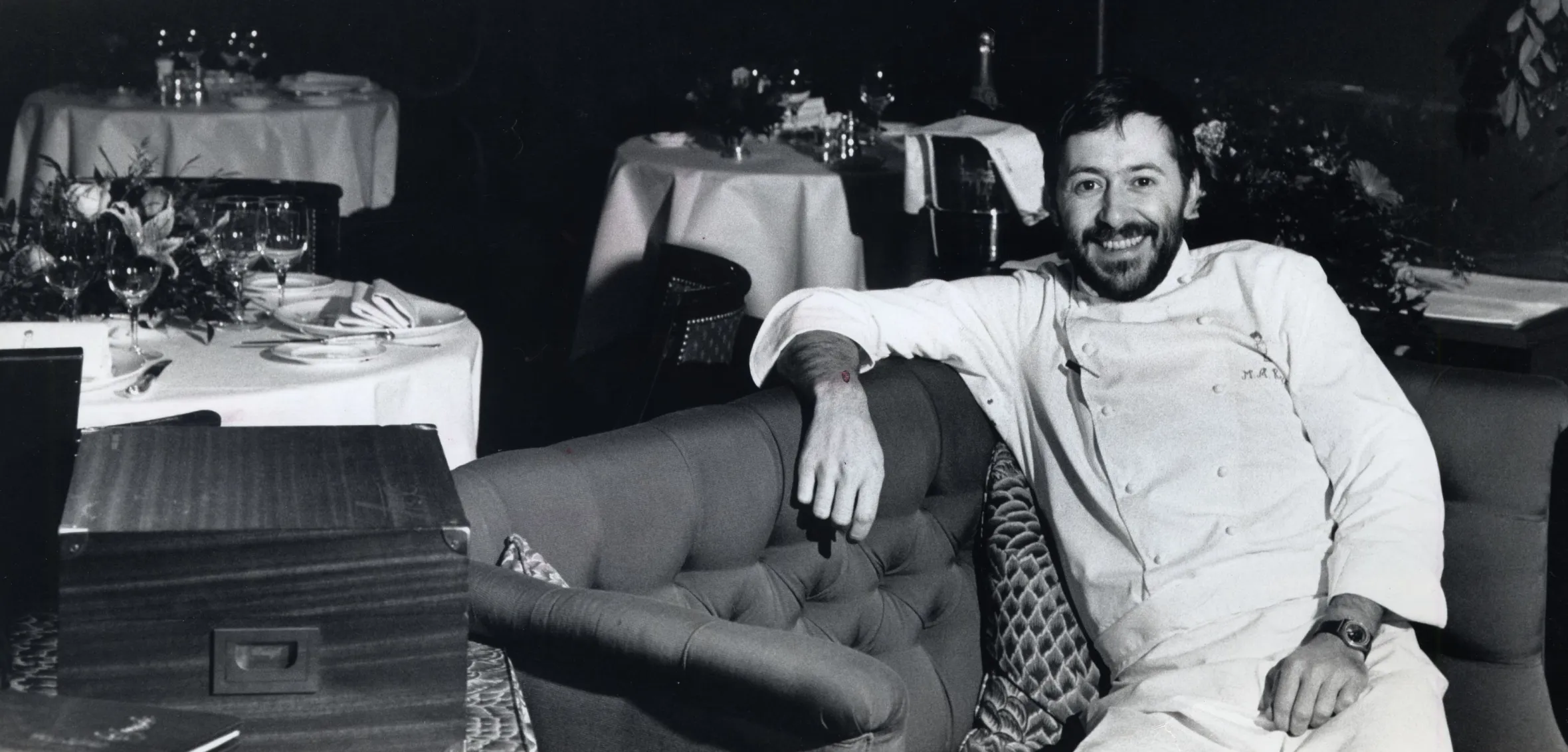 Chef Michel Roux Jnr of Le Gavroche Restaurant smiling and sitting on a couch.