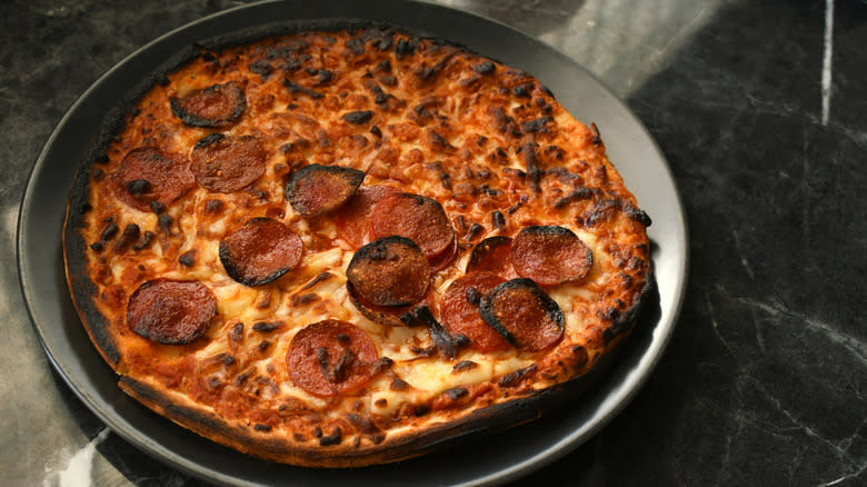 Nearly burnt pizza on grey plate