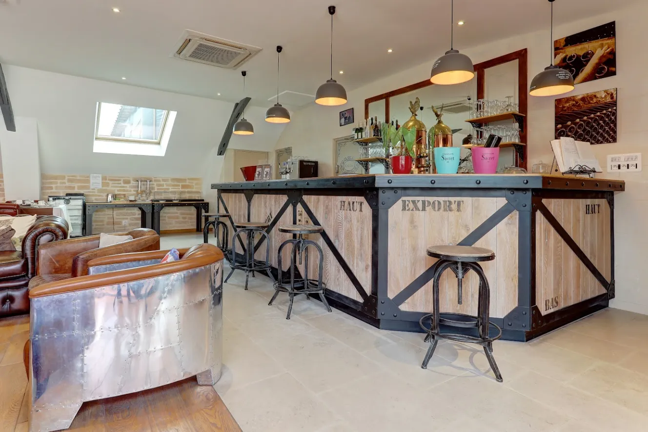 Lounge area at Domaine Sacret with an industrial-style bar, brown leather armchairs, and a buffet station.