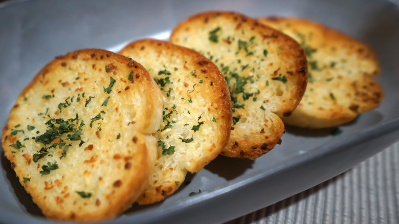 A plate of toasty garlic bread slices on a gray dish