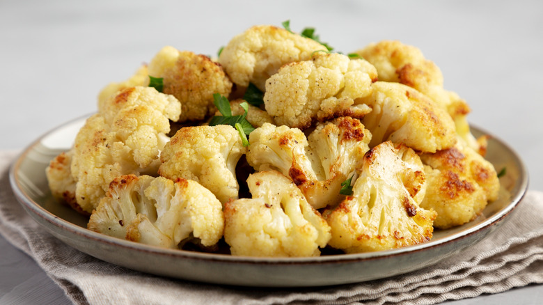 A large pile of roasted cauliflower on a ceramic plate