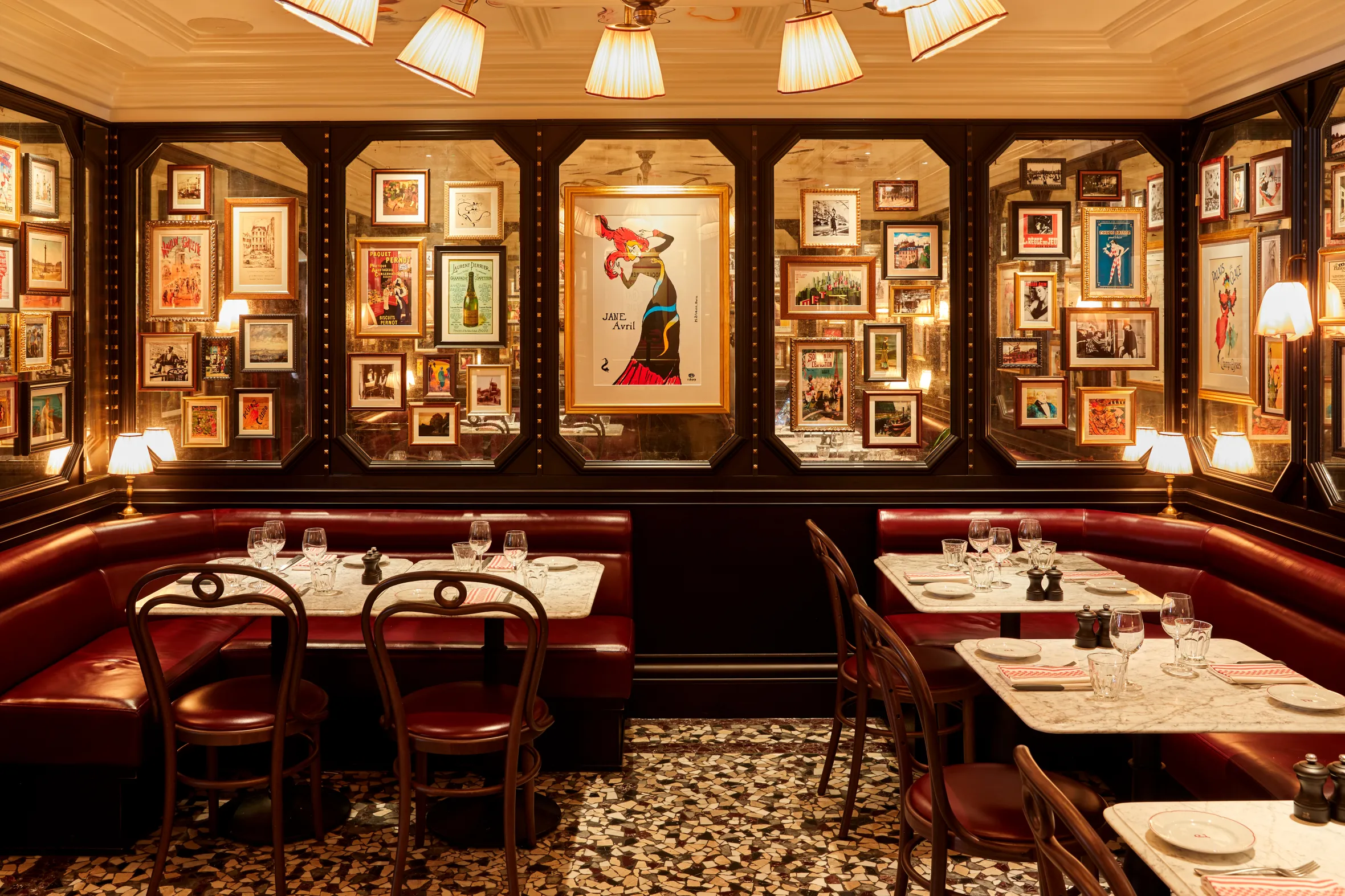 Interior of Josephine restaurant in Marylebone with red leather booths, tables with white marble tops, and walls adorned with framed art prints.