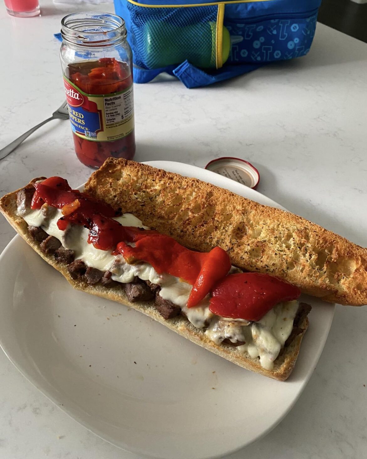 Steak sandwich on toasted garlic bread, melted mozzarella and roasted red peppers