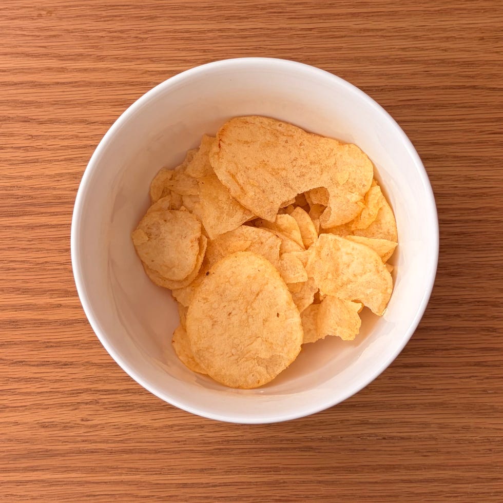 Bowl of potato chips on a wooden table.