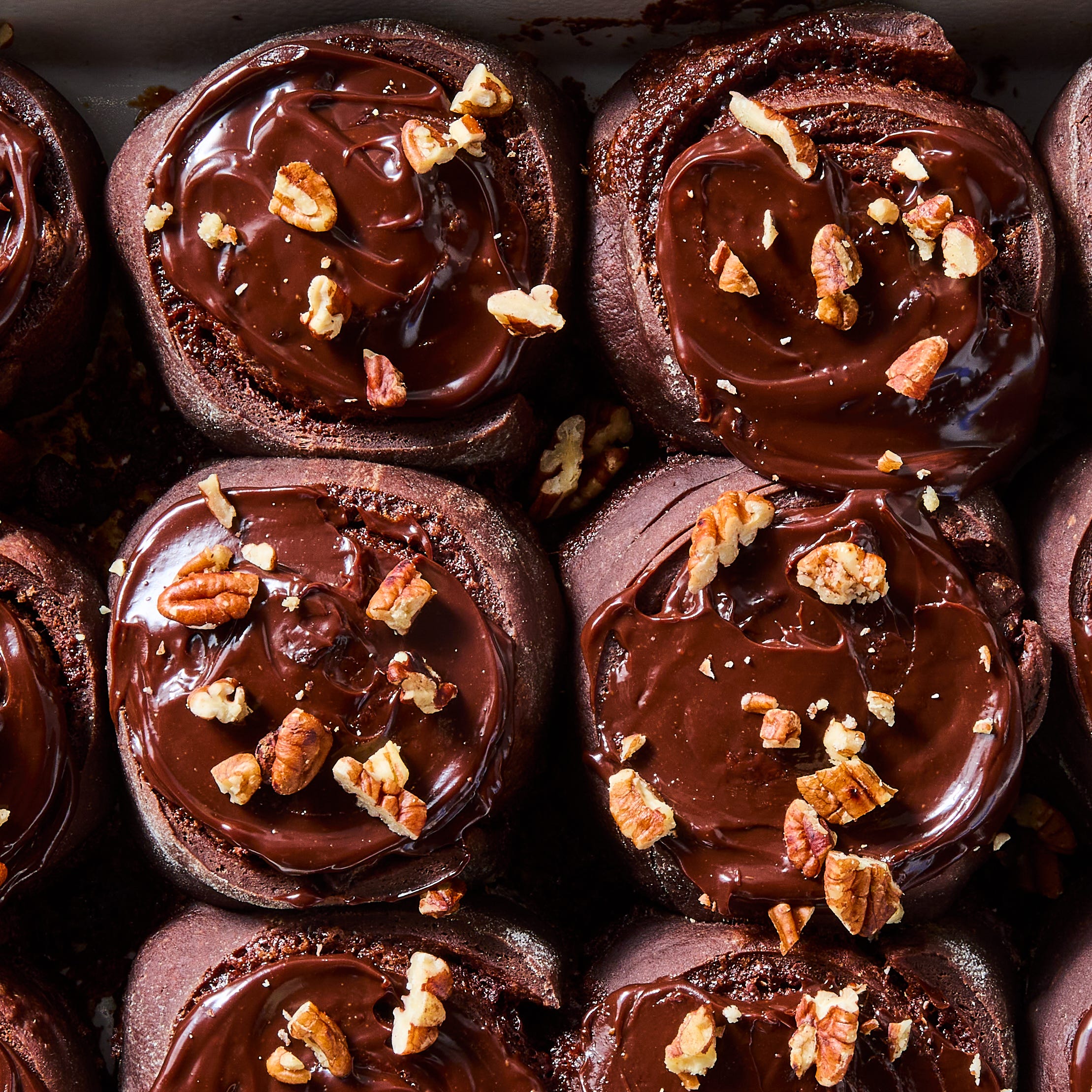 chocolate cinnamon rolls topped with a chocolate glaze and chopped pecans