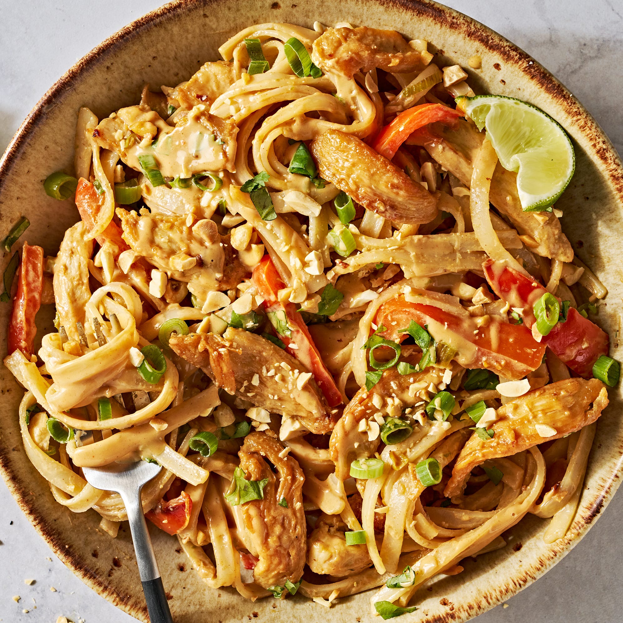 chicken with noodles and carrots in a creamy peanut lime sauce topped with peanuts