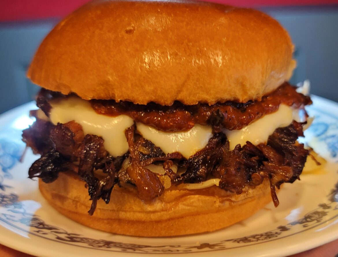 Carnitas, white onions, Oaxacan cheese, and homemade salsa on a toasted Brioche bun