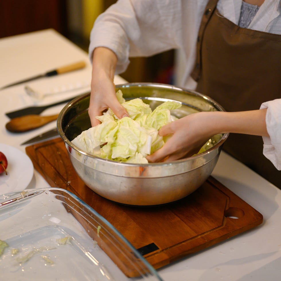 Cabbage is massaged in a bowl to soften the leaves, a key step in the viral “addictive cabbage” hack. This technique helps break down the texture and allows flavors to absorb more easily, creating a more tender, flavorful dish.