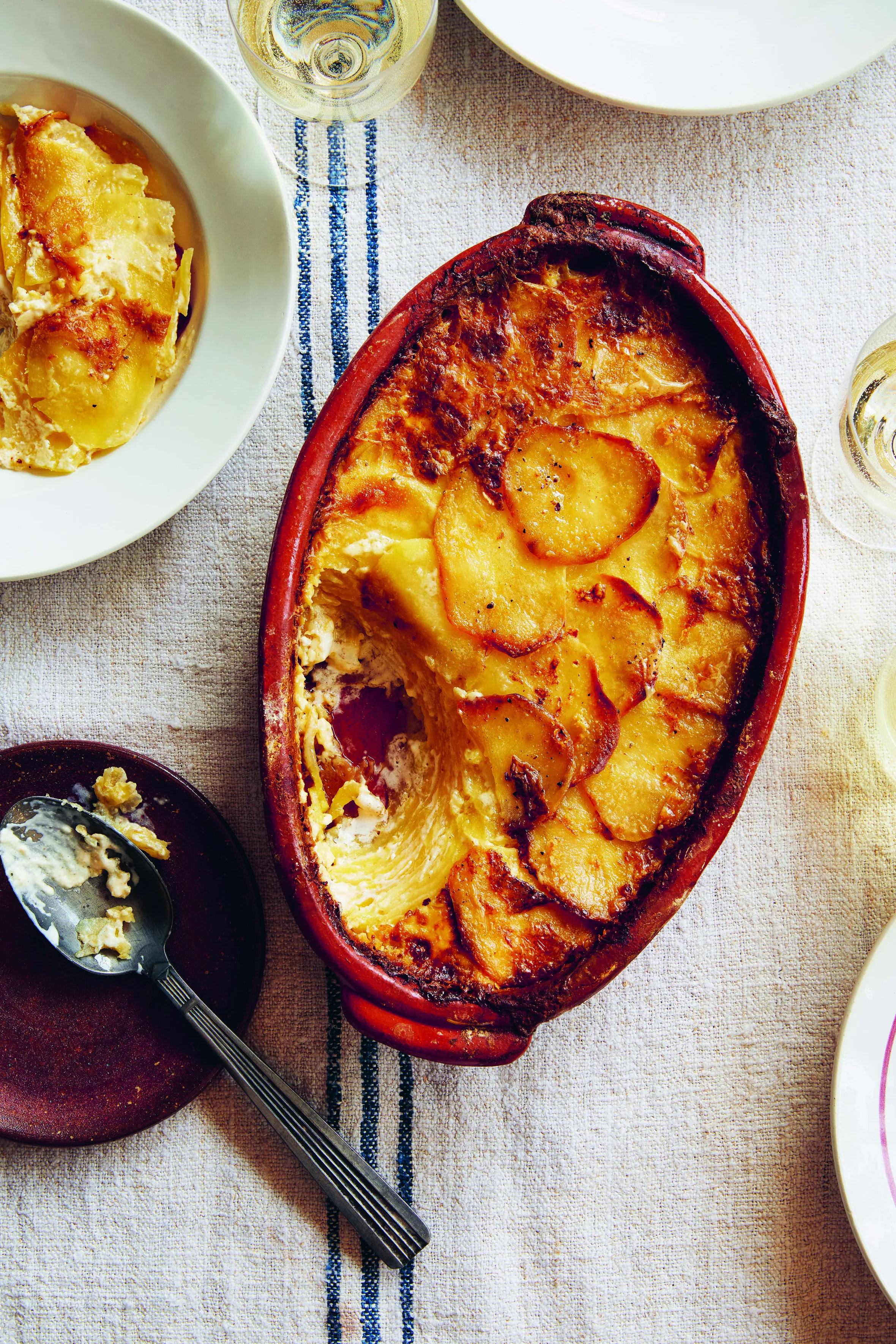 Dauphinois potatoes in a red dish with one serving on a plate.