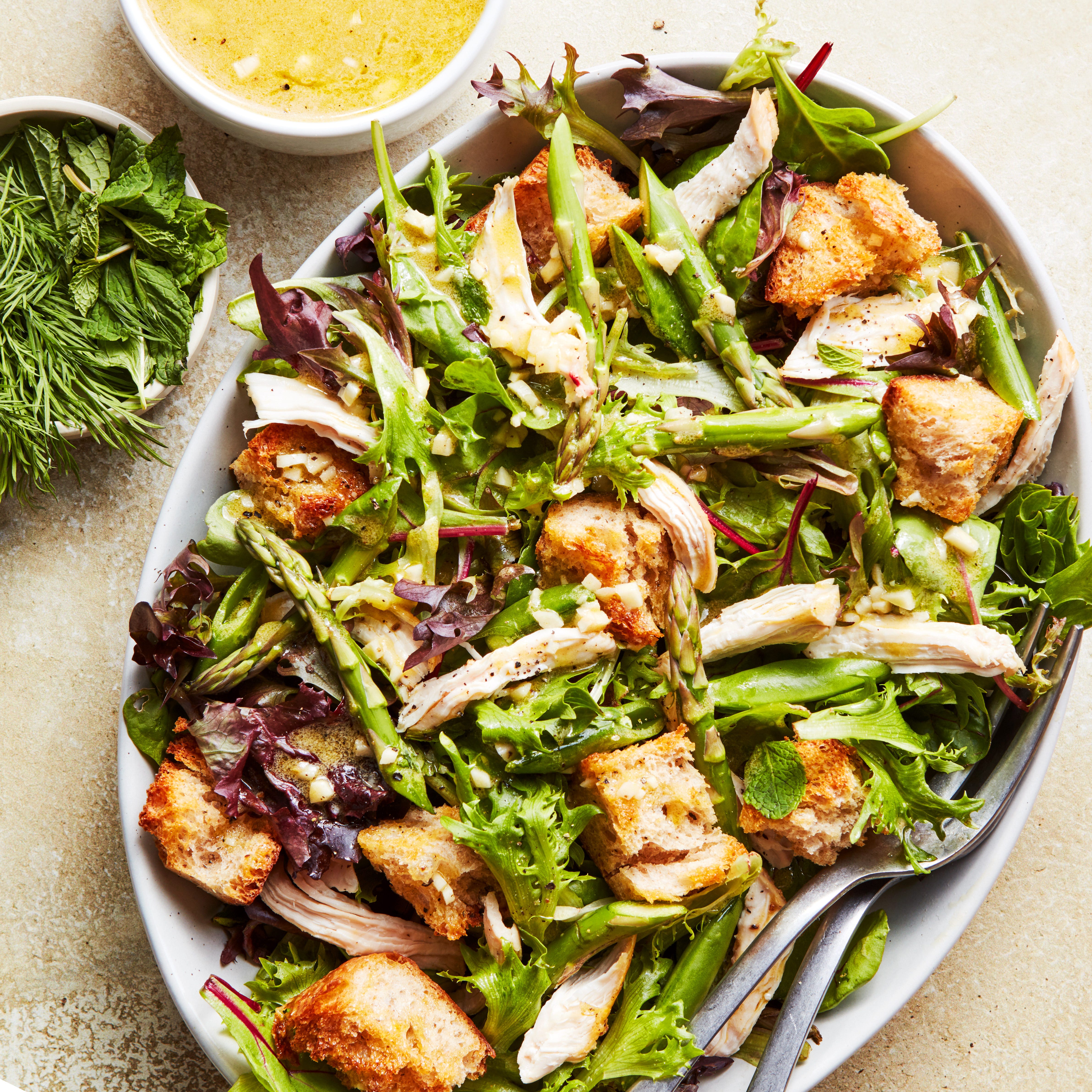 spring chicken panzanella salad topped with asparagus, peas, and shredded chicken